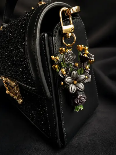 Onyx Bloom Charm — clipped to a black handbag
